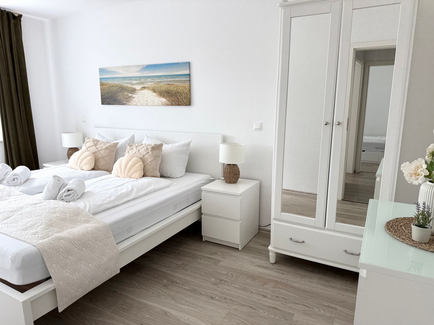 A bedroom with a bed, bedside tables, a wardrobe, a mirror, and a painting on the wall.