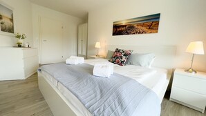 A hotel room with a bed, bedside tables, a wardrobe, and a painting on the wall. - A4.3-Bright, friendly apartment with partial sea view, for up to 7 people (Cuxhaven)