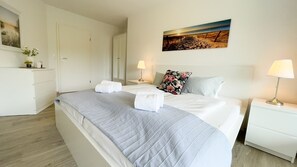 Ein Hotelzimmer mit Bett, Nachttischen, einem Kleiderschrank und einem Bild an der Wand.
