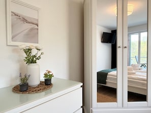 A room with a bed, a TV, and a window with a view of greenery.