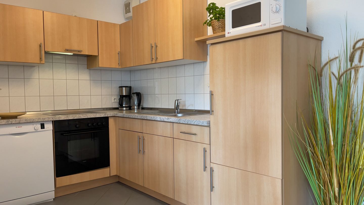 Eine Küche mit Holzausstattung, einer Mikrowelle, einer Kaffeemaschine und einem Geschirrspüler.