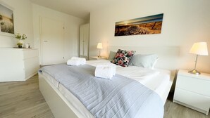A hotel room with a bed, bedside tables, a wardrobe, and a painting on the wall. - A3.3 - Bright vacation apartment, close to the beach for up to 7 people - House (Cuxhaven)
