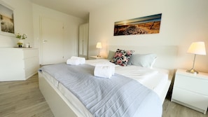A hotel room with a bed, bedside tables, a wardrobe, and a painting on the wall. - A3.3 - Bright vacation apartment, close to the beach for up to 7 people - House (Cuxhaven)