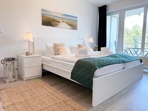 Un dormitorio moderno con una cama grande, mesitas de noche, una lámpara y vistas al exterior.