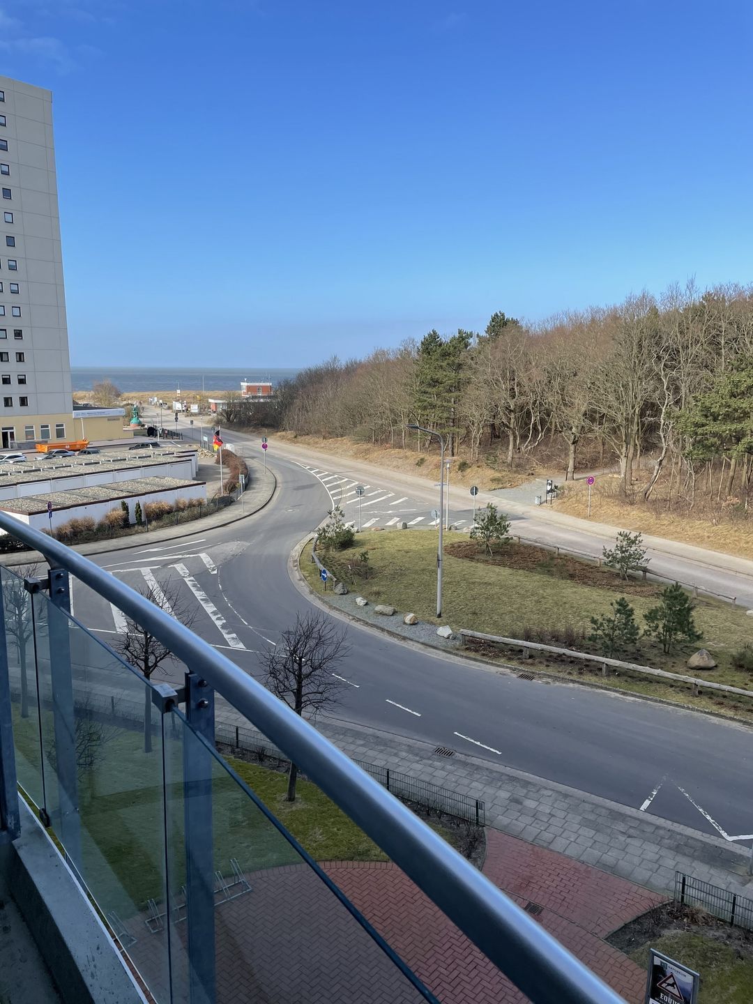 Une route qui serpente à travers un quartier résidentiel, avec un immeuble sur la gauche et un ciel dégagé.