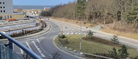 Una carretera serpentea por una zona residencial, con un edificio a la izquierda y cielo despejado.