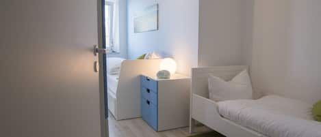 Un dormitorio con cama, mesita de noche, lámpara y un cuadro en la pared.