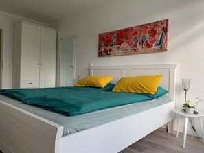 Une chambre à coucher avec un lit, une armoire blanche et un tableau accroché au mur.