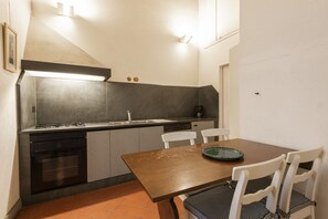 Una cocina compacta con estufa, lavaplatos y lavamanos, una mesa de comedor con sillas y un ventanal pequeño.