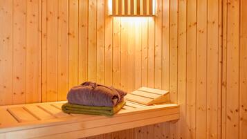 A wooden sauna with a bench, towels, and a light fixture.
