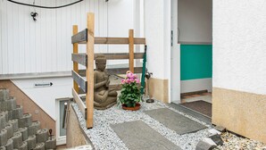Un pequeño espacio al aire libre con un banco de madera, una estatua y una planta en maceta.