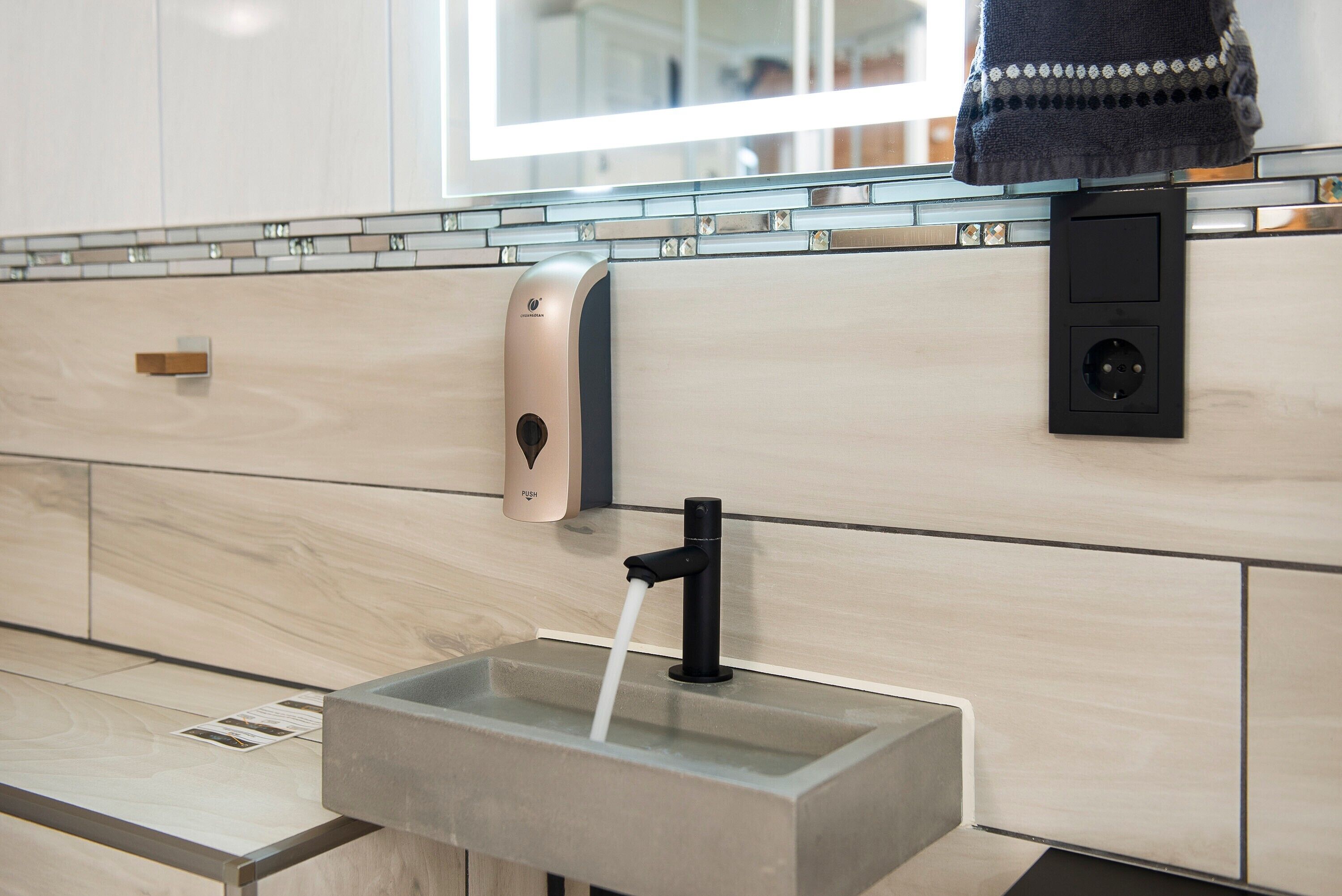 Un baño moderno con lavamanos empotrado, dispensador de jabón y barra para toallas.