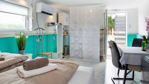 Habitación de hotel con cama, una mesita, una silla, planta en maceta y vistas al exterior.
