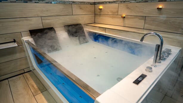 Un baño moderno con una bañera grande, una zona de ducha y un lavabo con mampara de cristal.