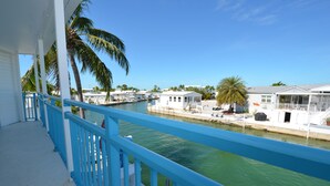 A balcony with a blue railing overlooking a marina with boats and palm trees. - Relaxing Waterfront Escape Near Key West - Venture Out Unit 410 (Cudjoe Key)