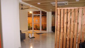 Un moderno vestíbulo con un separador de vidrio, una recepción y una zona de estar.