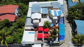 Vista aérea de un resort con varias edificaciones, una piscina y palmeras circundantes.