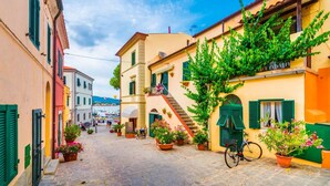 A cobblestone street lined with colorful buildings, a bicycle, and potted plants. - Le Mimose - Two-Room Apartment (Campo nell'Elba)