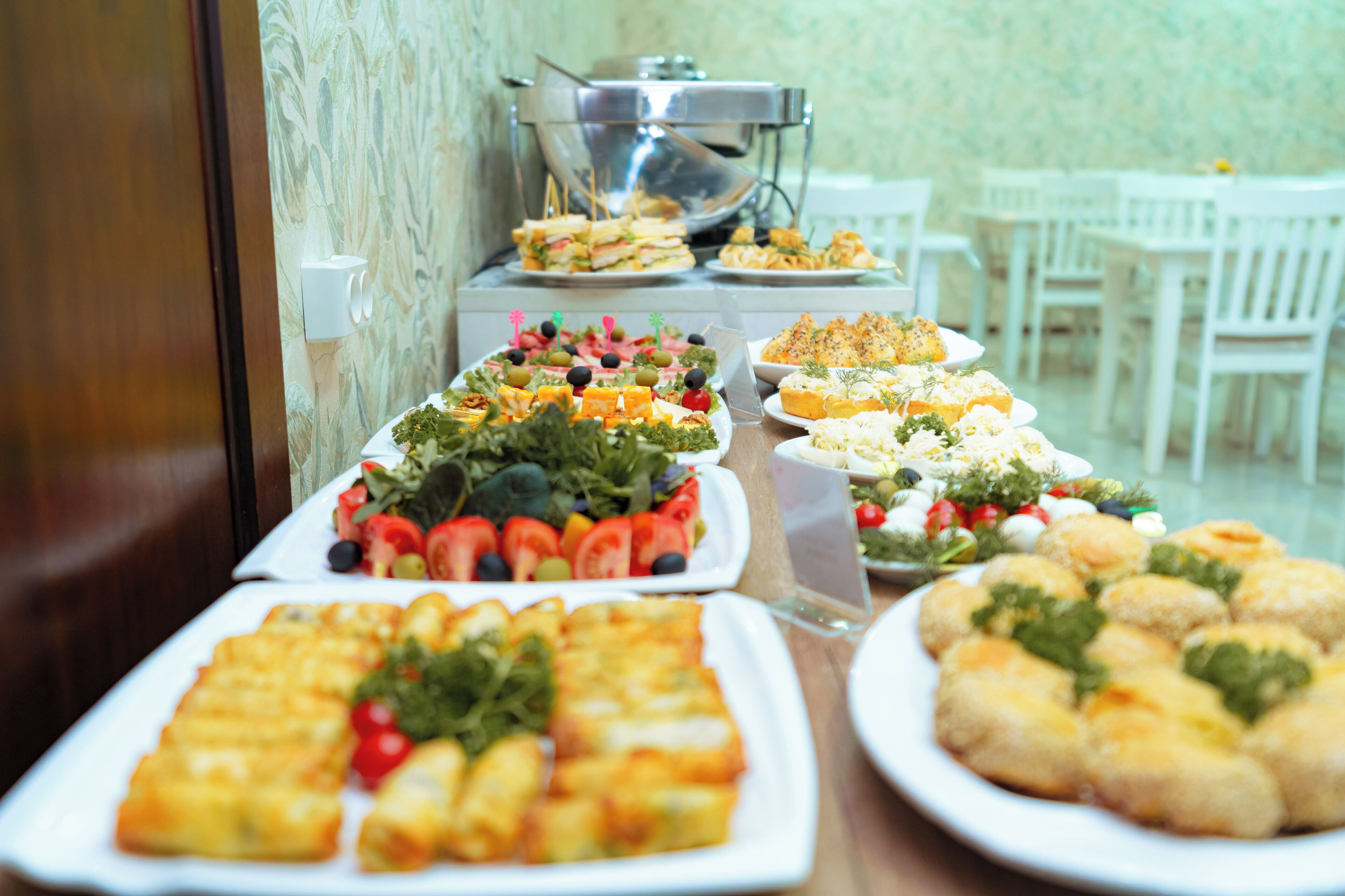 A buffet table with various dishes including salads, sandwiches, and appetizers.