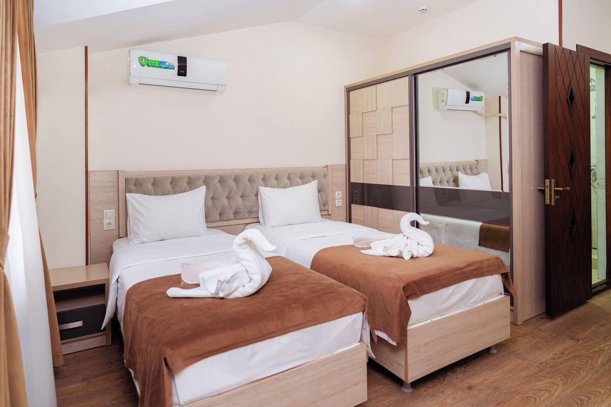 Habitació d'hotel amb dos llits, un armari i un aparell d'aire condicionat.