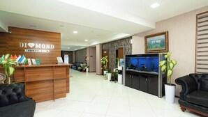 A reception area with a wooden desk, black leather sofas, a large aquarium, and potted plants.