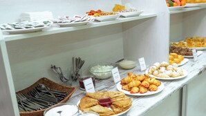 A buffet with various food items including pastries, fruits, and condiments.