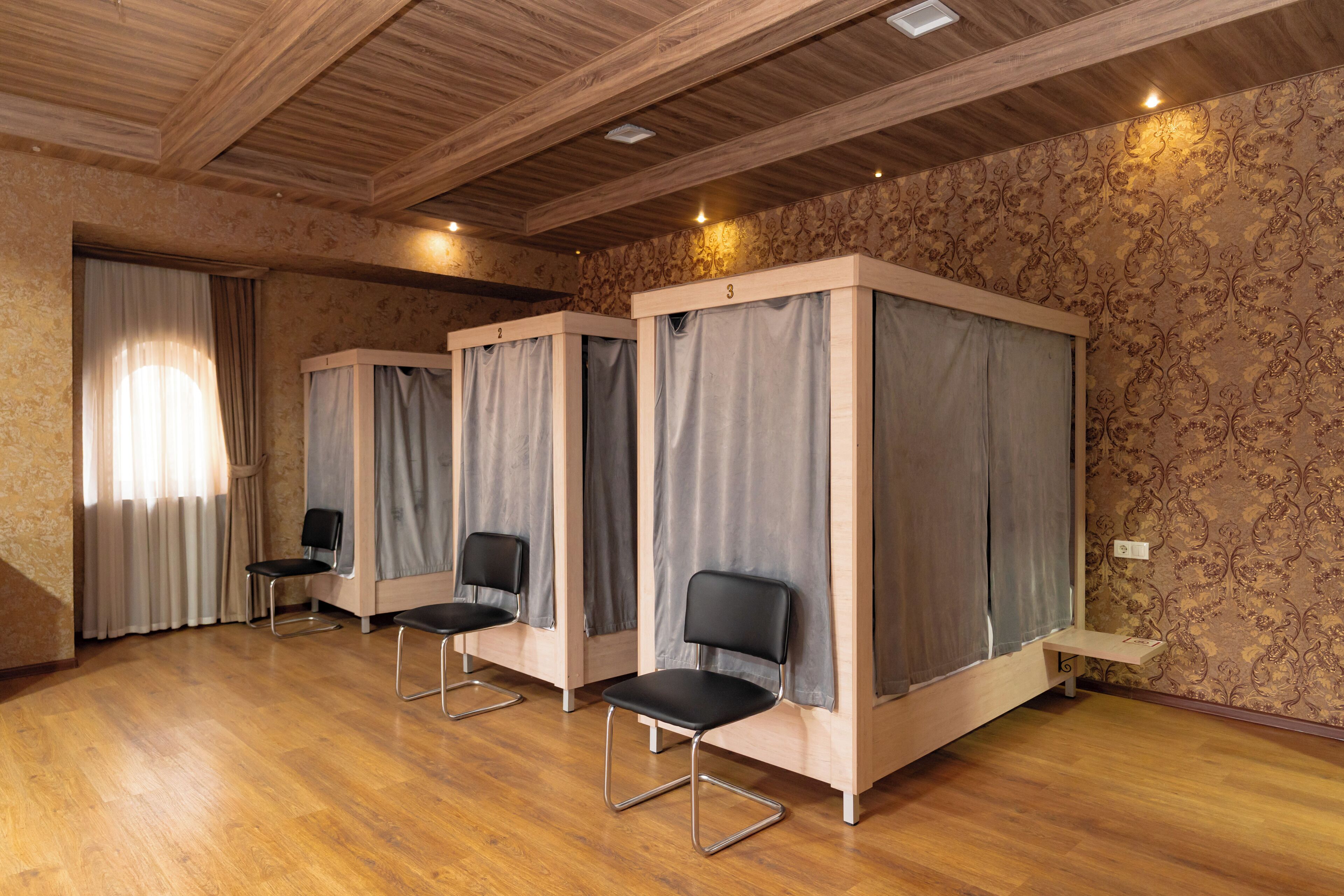A room with four single beds, each with a curtain and a small table.