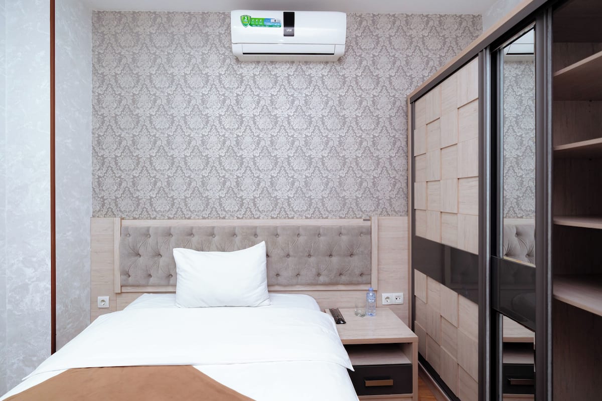 Habitació d'hotel amb un llit, una petita taula de nit, un aparell d'aire condicionat i una porta corredissa per a l'armari.
