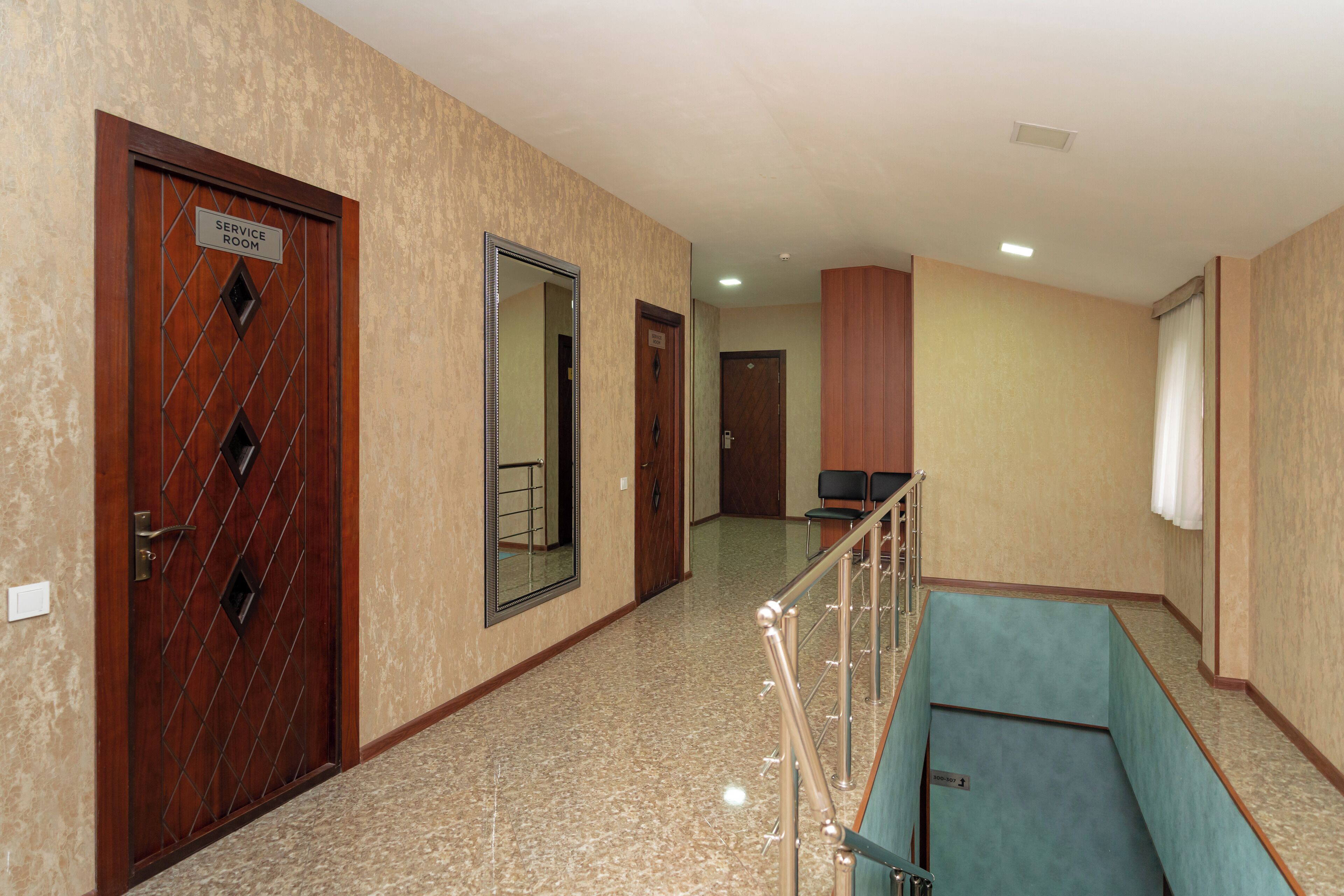 A hotel corridor with a service room, a mirror, and a staircase.