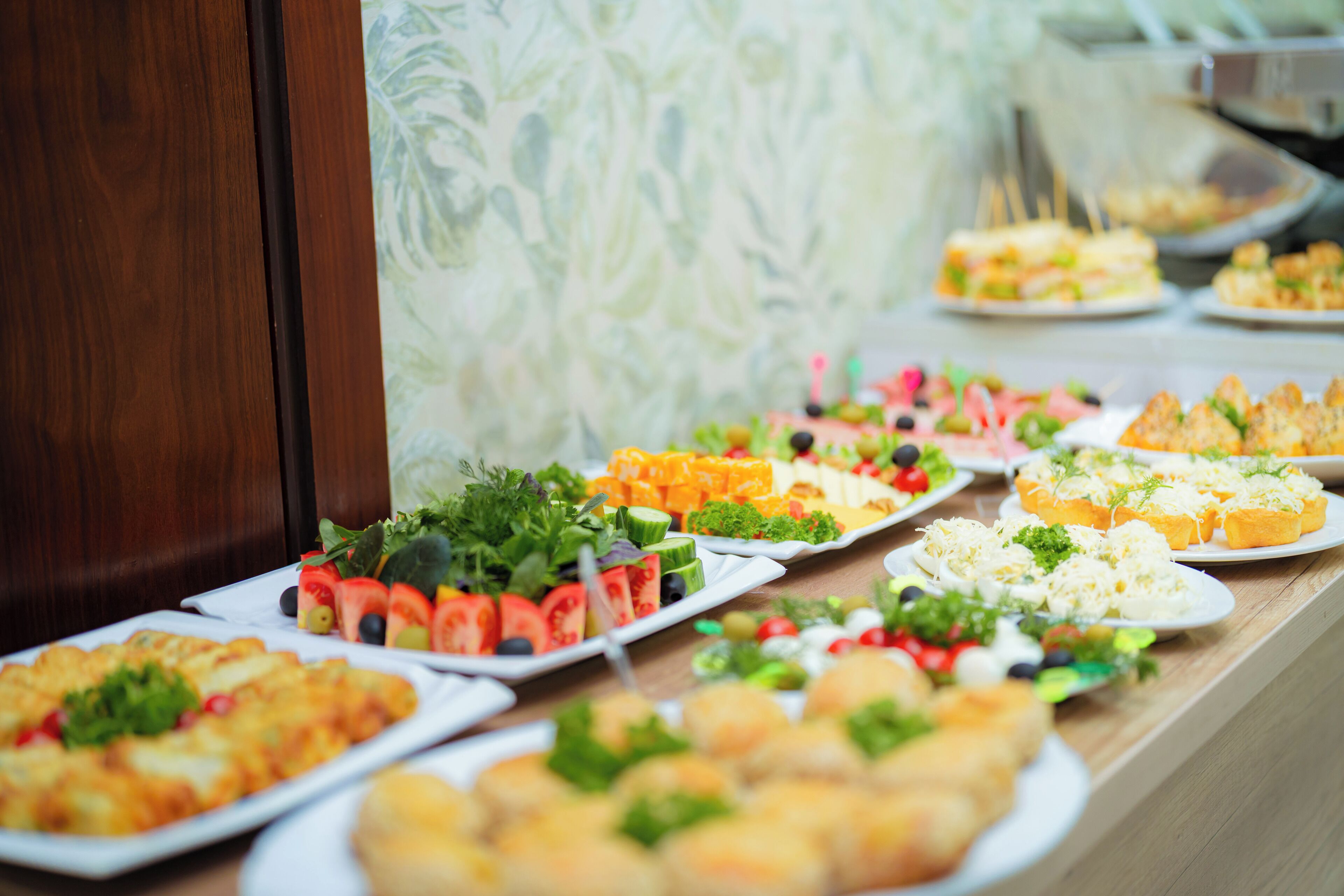 A buffet with various dishes including salads, cheeses, and bread.