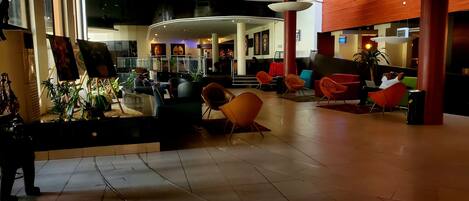 A spacious lobby with modern seating, a reception area, and a display of artwork.