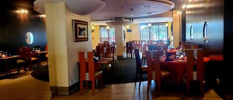 A restaurant with multiple dining areas, including booths and tables, with a tiled floor and a ceiling with recessed lighting.