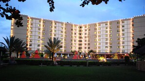 Ein mehrstöckiges Hotel mit einer symmetrischen Fassade, gleichmäßig angeordneten Fenstern und einem gepflegten Rasen mit Zierelementen.