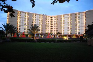 Un hotel de varios pisos con una fachada simétrica, ventanas distribuidas uniformemente y un césped cuidado con estructuras decorativas.