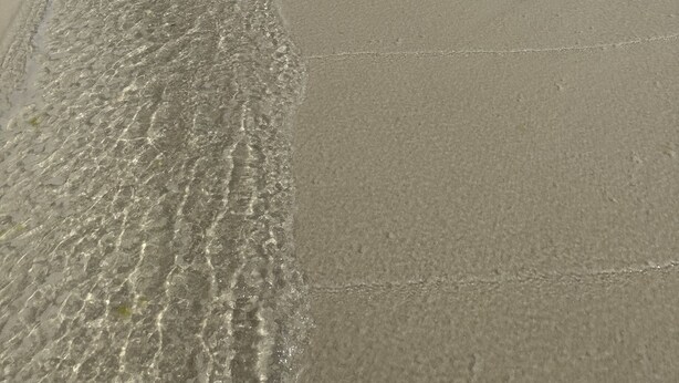 Una spiaggia con acque cristalline e una battigia sabbiosa.