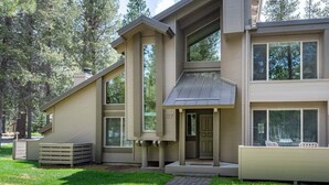 Et moderne hus i to etager med fladt tag, store vinduer og en overdækket veranda.