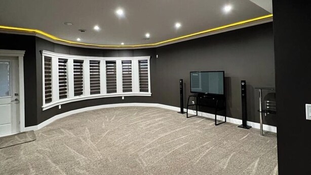 A home theater room with a curved seating area, a large screen, and a speaker system. - Beautiful 1 bedroom Basement in an Acreage (Delacour)