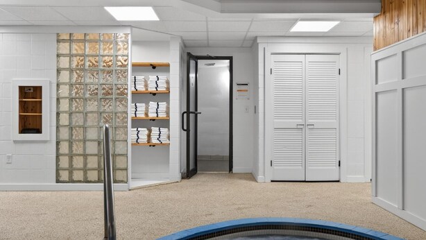A room with a tiled floor, a glass partition with shelves, a door, and a pool area. - Pinnacle B18 (Killington)