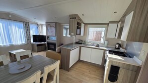 Een moderne keuken met een ingebouwde kookplaat, een eethoek met tafel en stoelen, en een televisie in de hoek.