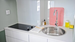A kitchen with a stainless steel sink, a red grid-patterned cutting board, and a white countertop. - Red Red Wine in Lisbon by Misha s Place 3B (Lisbon)
