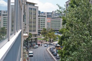 Straßenansicht mit modernen Gebäuden, parkenden Autos und einem Bus.