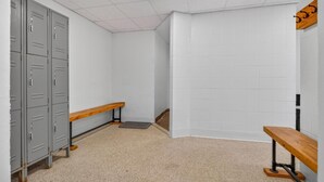 A locker room with grey lockers, a wooden bench, and a tiled wall. - Pinnacle B09 (Killington)