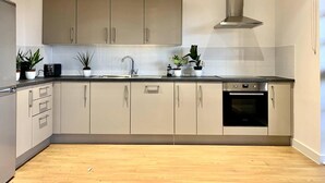 Uma cozinha moderna com armários de cor clara, um exaustor de aço inoxidável e um forno embutido.