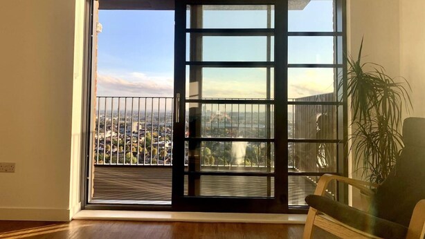 Quarto com uma grande porta de vidro deslizante que dá para uma varanda com vista para a cidade.