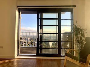 A room with a large sliding glass door leading to a balcony with a city view.