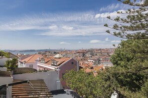 Stadtbild mit terrakottafarbenen Dächern, blauem Himmel und Blick auf das Meer.