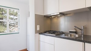 A modern kitchen with white cabinets, a stainless steel sink, and a gas stove. - The Castle Life in Lisboa Ciudad (Lisbon)