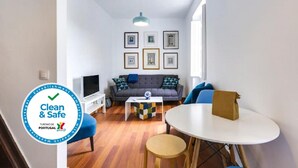 A modern living room with a grey sofa, blue armchairs, a coffee table, and a TV. - The Castle Life in Lisboa Ciudad (Lisbon)