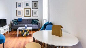 A modern living room with a grey sofa, blue armchairs, a coffee table, and a TV. - The Castle Life in Lisboa Ciudad (Lisbon)