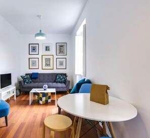 A modern living room with a grey sofa, blue armchairs, a coffee table, and a TV. - The Castle Life in Lisboa Ciudad (Lisbon)